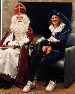 Sinterklaas en roetveegpiet met een kindje op schoot.